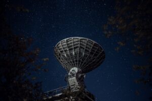radio telescope against sky with stars